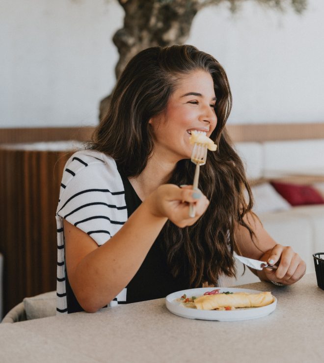 Woman smiling while eating breakfast croissant at GAL Split terrace