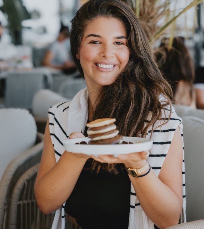 Smiling guest holding plate of pancakes with chocolate at GAL Split café