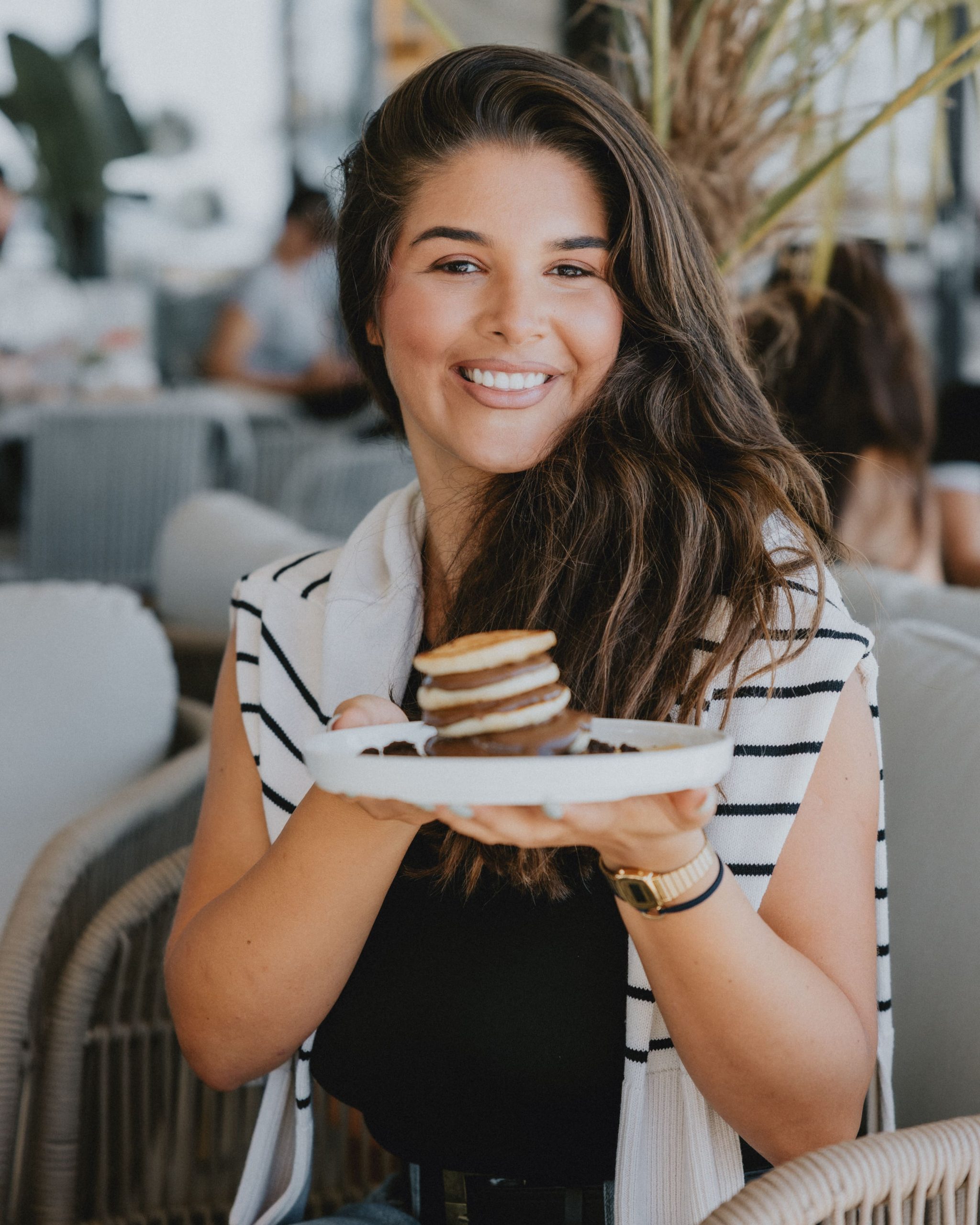Smiling guest holding plate of pancakes with chocolate at GAL Split café